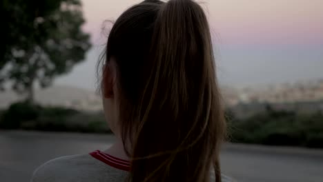 Long-hair-girl-on-the-roadside-with-the-car-traffic-turns-her-back-to-the-camera.