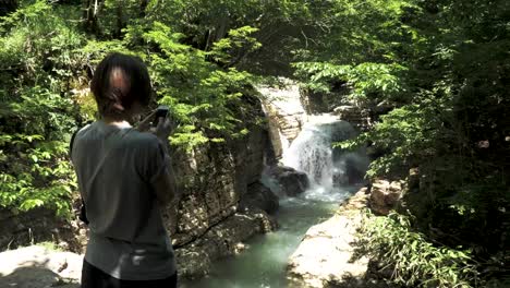 Junges-Mädchen-nimmt-Foto-des-kleinen-Wasserfalls,-Georgien