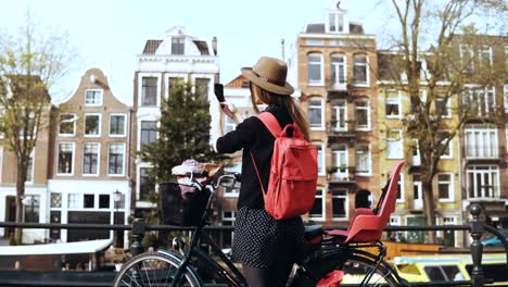 Chica-con-bicicleta-enviando-video-a-amigos-en-línea.-Blogs-de-mujer-bastante-Europea-en-las-redes-sociales.-Vista-posterior.-4K