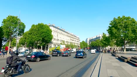 Morning-traffic-with-city-tour-bus-at-Place-de-la-Republique-and-bronze-statue-of-Marianne,-holding-olive-branch-is-in-the-square-center