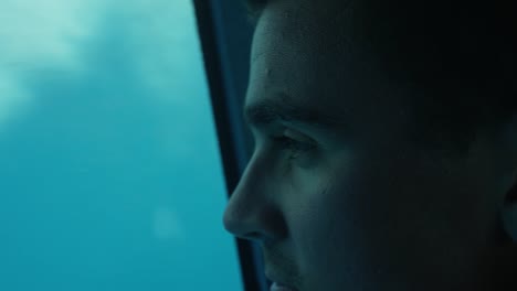 Primer-plano-de-un-hombre-mirando-la-vida-bajo-el-agua-mientras-que-en-el-barco-con-el-fondo-de-cristal.