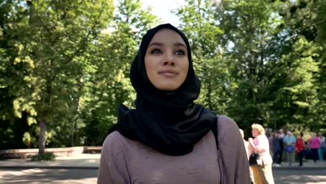 Young-happy-muslim-girl-in-hijab-is-smiling-and-going-to-university-in-daytime-in-summer,-religious-concept,-studying-concept