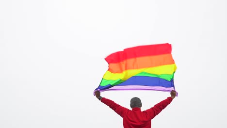 hombre-levantar-bandera-LGBTI-de-color-arco-iris-ondeando-en-duro-viento-en-el-mirador-de-alta-montaña