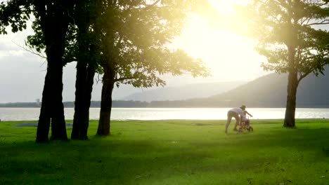 Asian-son-practice-to-ride-a-bicycle-with-his-father,-Happy-family-in-the-natura-park,-4K-Video-Slow-motion