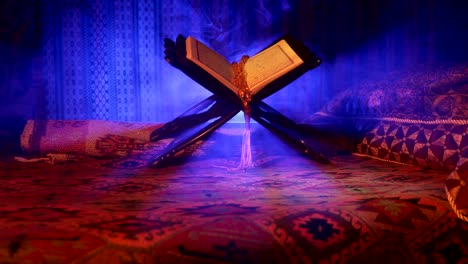 Open-holy-book-of-Muslims-on-stand-on-eastern-carpet-with-dark-toned-foggy-background.-Muslim-religion-concept.-Selective-focus.-Slider-shot.