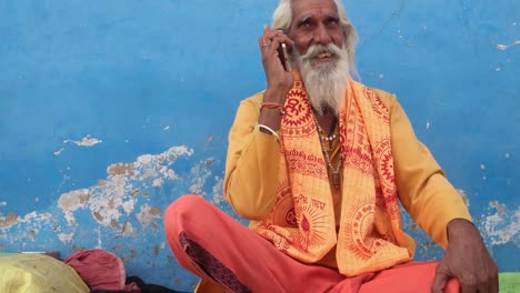 Wide-shot-of-an-Indian-sage-on-his-cell-phone,-moving-in,-in-Pushkar,-Rajasthan