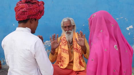 In-Rosa-Sari-Brautpaar-in-weißem-Kurta-und-roten-Turban-suchen-Segen-aus-einer-alten-hinduistischen-Sadhu-in-Safran-frisch-vermählte-Ehemann-Ehefrau