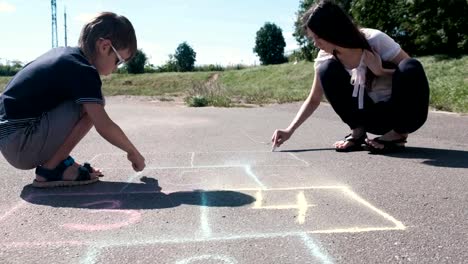 Mother-and-son-drawing-together-hopscotch-on-the-asphalt.