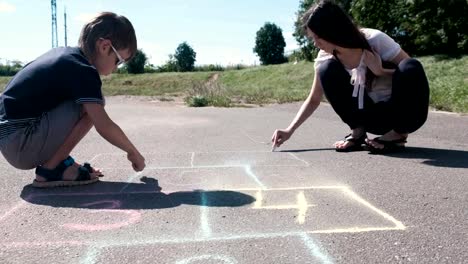 Mutter-und-Sohn-zusammen-Zeichnen-von-Himmel-und-Hölle-auf-dem-Asphalt.