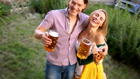 A-couple-of-young-people-at-the-Oktoberfest-festival-drink-beer-from-big-glasses.-The-girl-is-dressed-in-a-national-Bavarian-costume