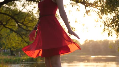 Frau-Figur-in-rot-transparent-Kleid-tanzen-und-drehte-sich-um-gegen-See-bei-Sonnenuntergang