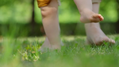 Piernas-de-mujer-y-bebé-caminar-sobre-la-hierba-descalzo