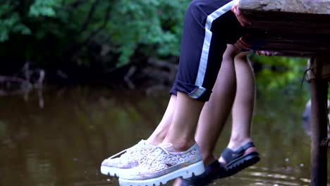 Teens-relaxes-by-the-river-sitting-on-the-edge-of-a-wooden-jetty.