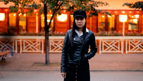 Time-lapse-portrait-of-tired-Asian-girl-standing-in-pedestrian-street-with-hand-in-pocket-and-looking-at-camera-then-leaving,-men-and-women-are-whizzing-around.