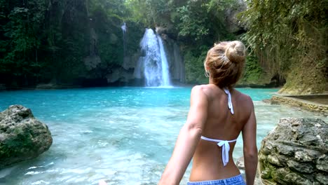 Follow-me-to-concept-young-woman-leading-boyfriend-to-amazing-waterfall,-shot-in-Cebu-Island,-Visayas-Islands,-Philippines.-Idyllic-tropical-travel-journey-vacations-concept.-4K-video