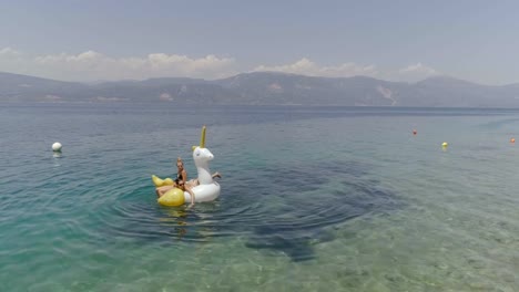 Vista-aérea-de-dos-mujeres-flotando-en-inflable-en-Panagopoula,-Grecia.