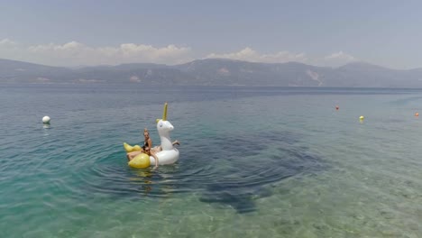 Aerial-view-of-two-women-floating-on-inflatable-in-Panagopoula,-Greece.