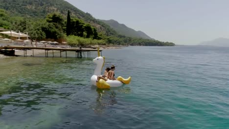 Vista-aérea-de-dos-mujeres-flotando-en-inflable-en-Panagopoula,-Grecia.