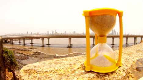 Bandra-Worli-Sea-Link-Mumbai-in-front-small-sandglass-sand-slowly-fall-hand-turns-it