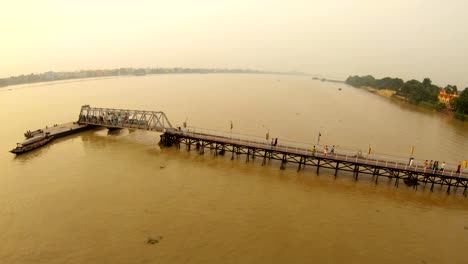 People-on-pier-on-river-Hooghly-Hindu-temple-on-bank-Ramakrishna-mission-sunset-delta-of-Ganges-Kolkata