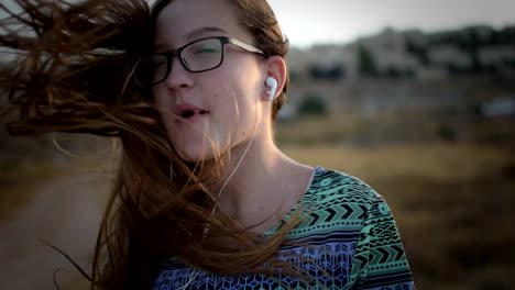 Teenager-Mädchen-mit-eyeglasses-hören-Sie-die-Musik-und-Gesang-im-Freien