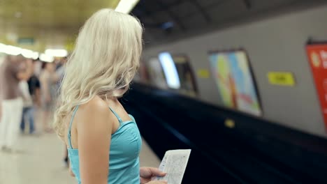 Süße-blonde-mit-einer-Karte-in-Ihre-Hände-warten-auf-die-U-Bahn-Auto