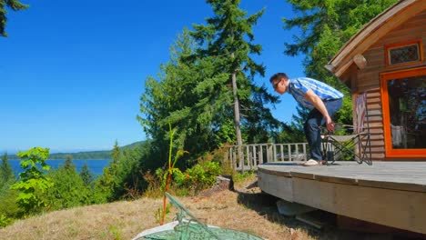 Video-Summer-Cabin-view-from-Bluff,-Man-Walks-and-Sits-in-Chair