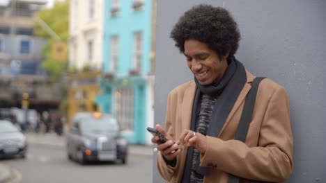 Joven-usando-el-teléfono-en-calle-muy-transitada-de-la-ciudad