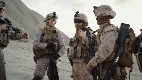Gruppe-von-Soldaten-steht-in-einem-Kreis-und-hört-Aufträge-von-Commander-während-Briefing-vor-der-militärischen-Operation-in-der-Wüste.-zeitlupe.