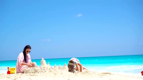 Mama-und-die-kleinen-niedlichen-Baby-machen-Sandburg-am-tropischen-Strand