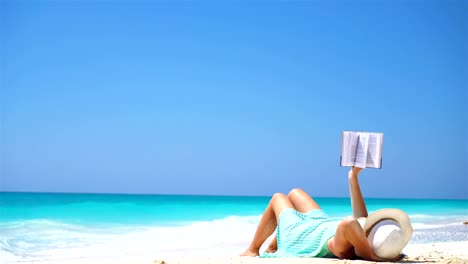 Young-woman-reading-book-during-tropical-white-beach