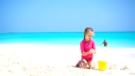 Adorable-little-girl-playing-with-beach-toys-on-white-sandy-beach