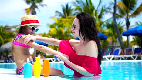 Young-mother-applying-sun-cream-to-kid-nose-in-swimming-pool.-The-concept-of-protection-from-ultraviolet-radiation