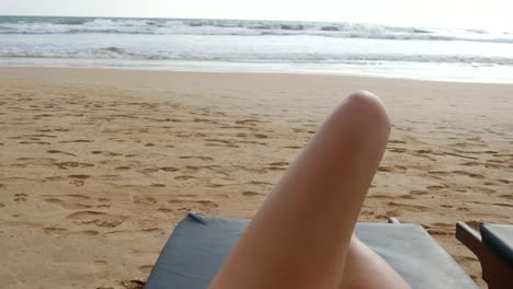 Sicht-der-jungen-Frau-liegt-auf-der-Liege-am-Meer-und-Solarium.-Weibliche-Beine-auf-Chaiselongue,-entspannen-und-genießen-während-der-Sommerferien-am-Ocean-Beach.-Fuß-des-Mädchens-auf-dem-Kurort.-Pov-hautnah