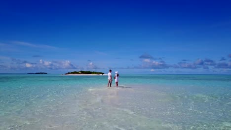 v03942-fliegenden-Drohne-Luftaufnahme-der-Malediven-weißen-Sandstrand-2-Personen-junges-Paar-Mann-Frau-romantische-Liebe-auf-sonnigen-tropischen-Inselparadies-mit-Aqua-blau-Himmel-Meer-Wasser-Ozean-4k