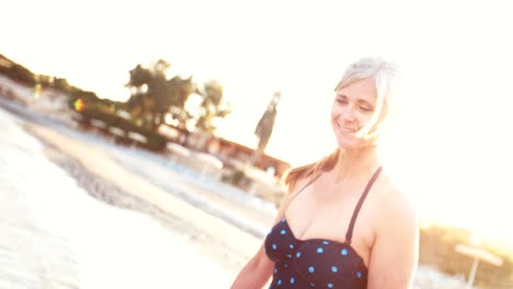 Ältere-Frau-im-Badeanzug-zu-Fuß-am-Strand-bei-Sonnenuntergang