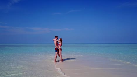 v03907-Aerial-flying-drone-view-of-Maldives-white-sandy-beach-2-people-young-couple-man-woman-romantic-love-on-sunny-tropical-paradise-island-with-aqua-blue-sky-sea-water-ocean-4k