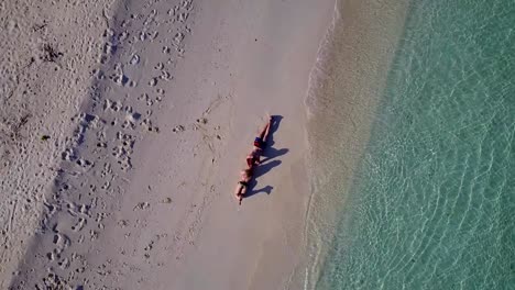 v03890-Aerial-flying-drone-view-of-Maldives-white-sandy-beach-2-people-young-couple-man-woman-romantic-love-on-sunny-tropical-paradise-island-with-aqua-blue-sky-sea-water-ocean-4k