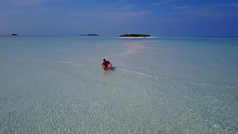 v03903-vuelo-drone-vista-aérea-de-Maldivas-playa-2-personas-pareja-hombre-mujer-amor-romántico-en-la-isla-de-paraíso-tropical-soleado-con-cielo-azul-aqua-agua-mar-4k