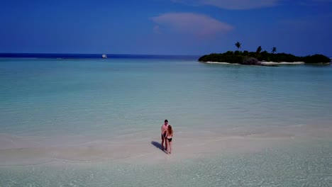 v03900-vuelo-drone-vista-aérea-de-Maldivas-playa-2-personas-pareja-hombre-mujer-amor-romántico-en-la-isla-de-paraíso-tropical-soleado-con-cielo-azul-aqua-agua-mar-4k