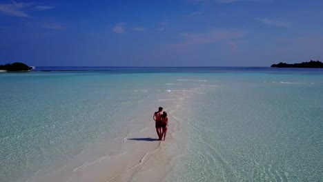 v04001-Aerial-flying-drone-view-of-Maldives-white-sandy-beach-2-people-young-couple-man-woman-romantic-love-on-sunny-tropical-paradise-island-with-aqua-blue-sky-sea-water-ocean-4k