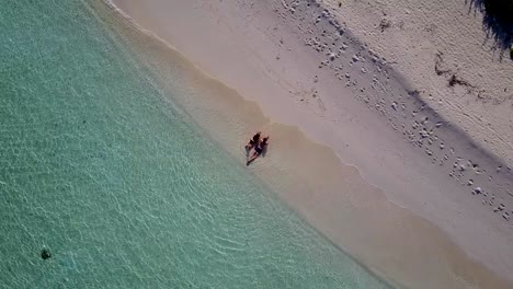 v04021-fliegenden-Drohne-Luftaufnahme-der-Malediven-weißen-Sandstrand-2-Personen-junges-Paar-Mann-Frau-romantische-Liebe-auf-sonnigen-tropischen-Inselparadies-mit-Aqua-blau-Himmel-Meer-Wasser-Ozean-4k