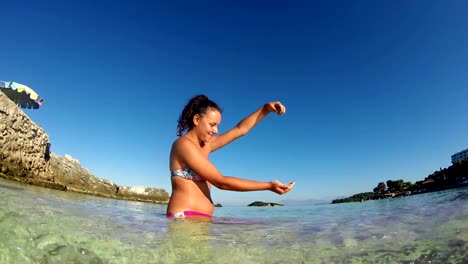 Una-chica-hermosa-con-arena-y-diversión-en-aguas-poco-profundas-del-mar