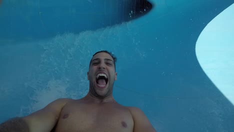 Man-having-fun-and-sliding-down-in-a-water-slide