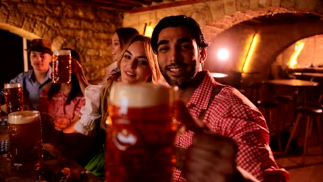 Young-multi-ethnic-friends-celebrating-Oktoberfest-with-beer-in-traditional-bar