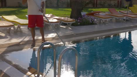 Hotel-worker-cleaning-water-in-swimming-pool,-cropped-view