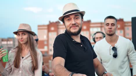 Pretty-brutal-Caucasian-man-in-hat-surrounded-by-friends-dancing-and-having-fun-at-rooftop-party