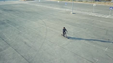 top-flying-view-of-young-teenager-riding-a-bmx-bicycle-on-the-asphalt-surface-in-the-city