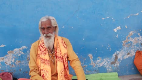 Hindu-Sadhu,-Heiliger-Mann,-sitzen-und-im-Gespräch-mit-Menschen-hinter-der-Kamera-in-Pushkar,-Rajasthan