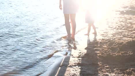 Schöne-blonde-Mutter-und-Tochter-Fuß-am-Strand-bei-Sonnenuntergang.-Close-up-Beine.